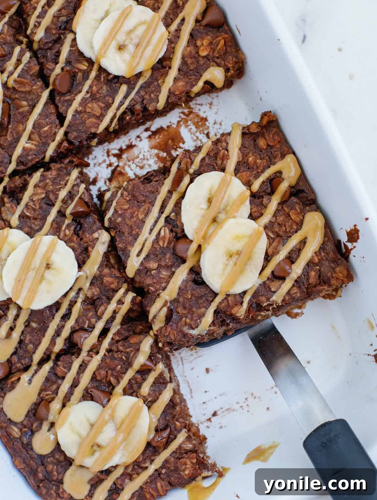A generous serving of baked chocolate oats, freshly baked and topped with vibrant banana slices and a rich drizzle of peanut butter, ready to be enjoyed as a wholesome breakfast.