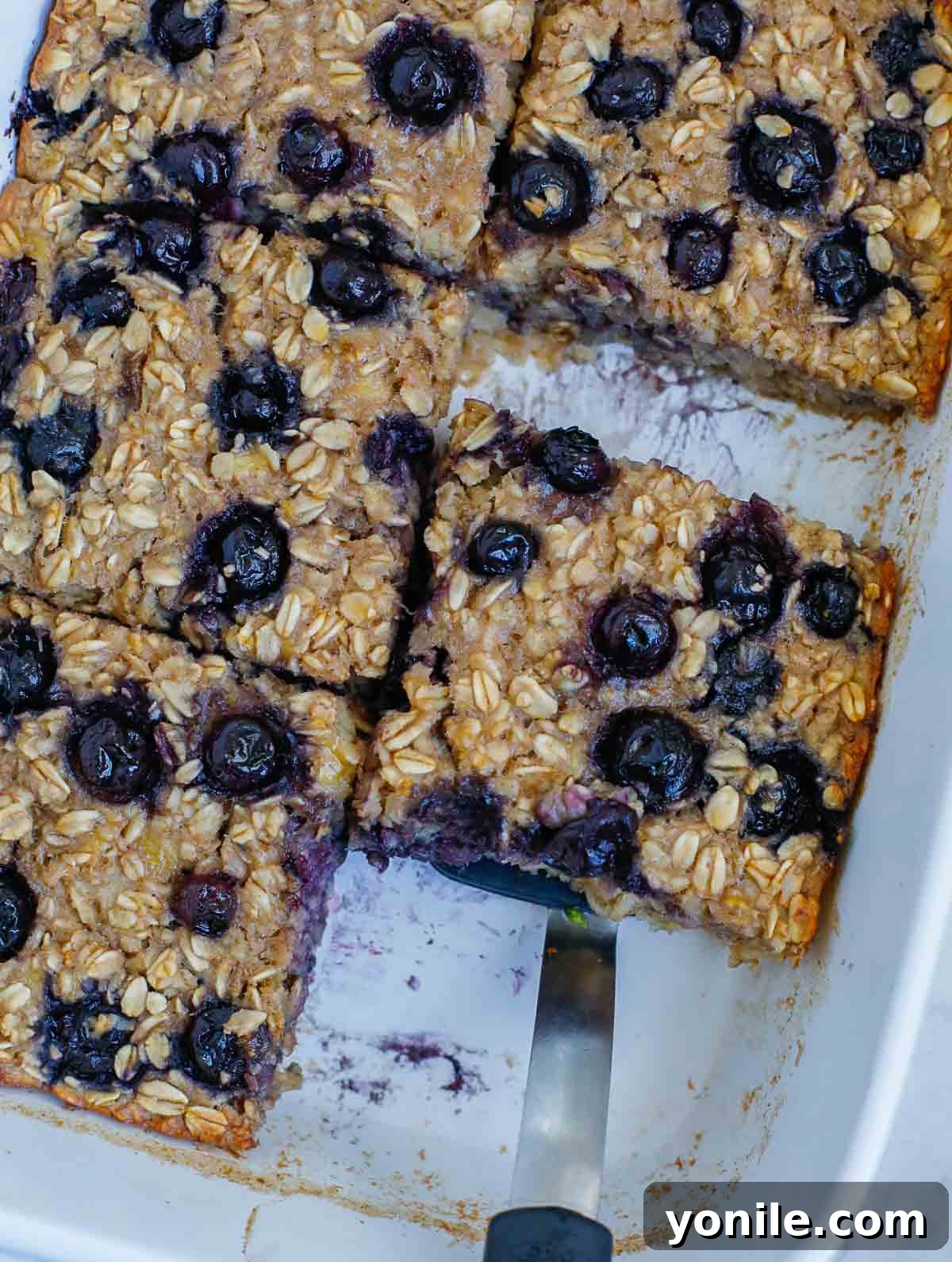 Close-up of baked blueberry oatmeal in a square dish, showing the crispy edges and tender center, ready to be served.