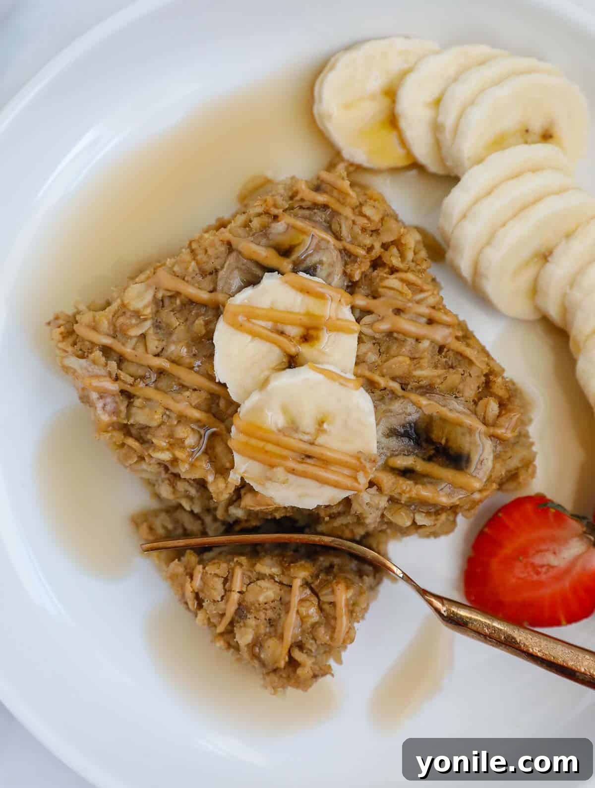 Baked peanut butter banana oatmeal on a plate with bananas and a fork. 