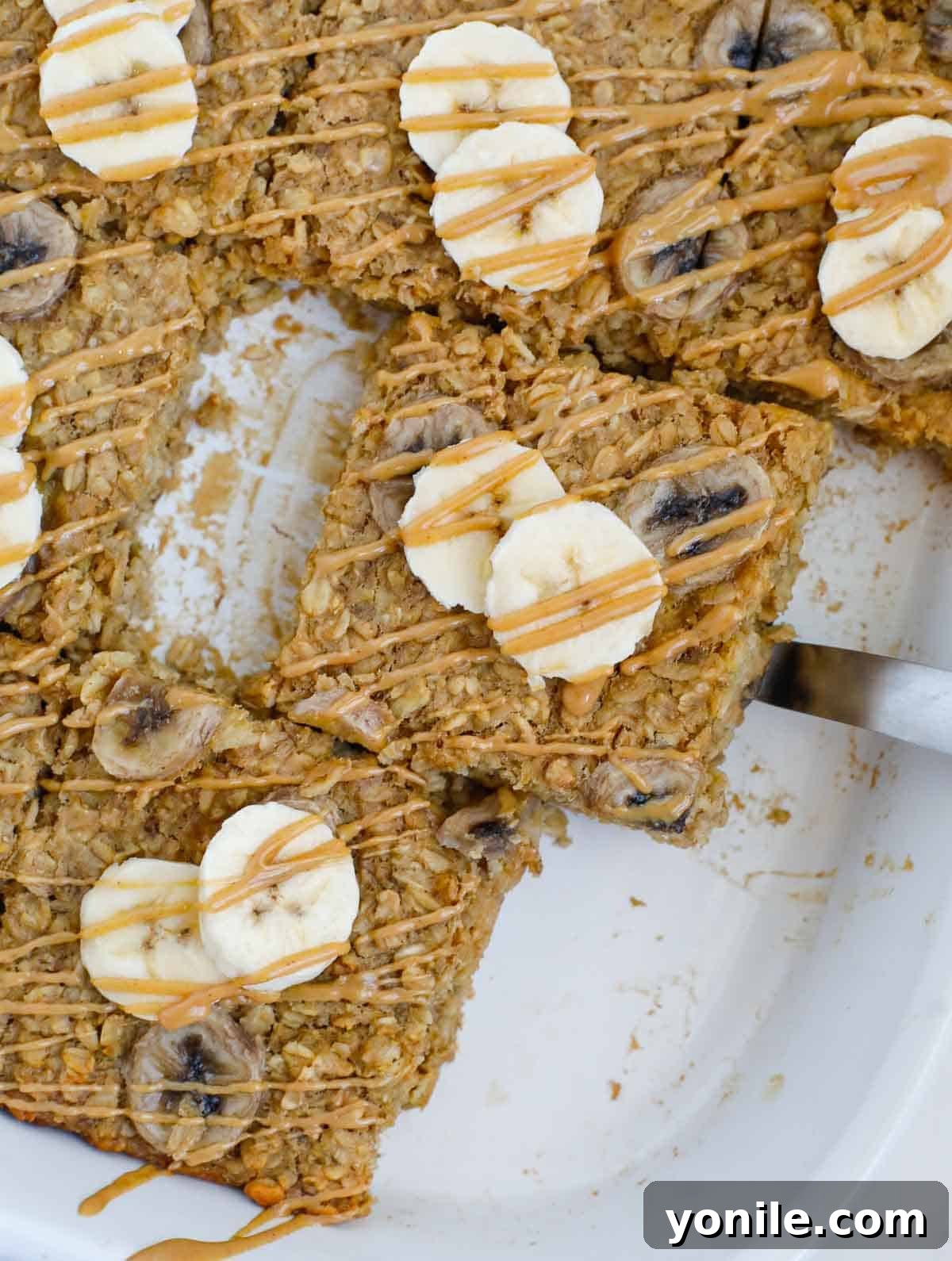 A slice of baked peanut butter banana oatmeal lifted out of a baking dish. 