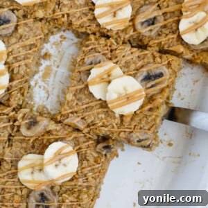 A slice of baked peanut butter banana oatmeal lifted out of a baking dish.
