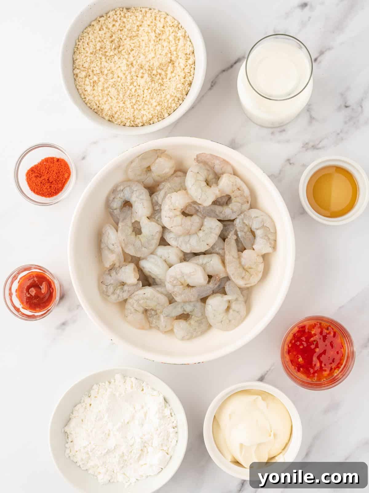 A flat lay photograph showcasing all the fresh ingredients required to make crispy air fryer Bang Bang shrimp and its creamy, spicy sauce.