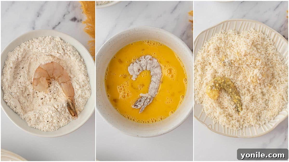 A hand is shown dredging a piece of shrimp through the flour mixture, illustrating the first step of the air fryer fried shrimp breading process.