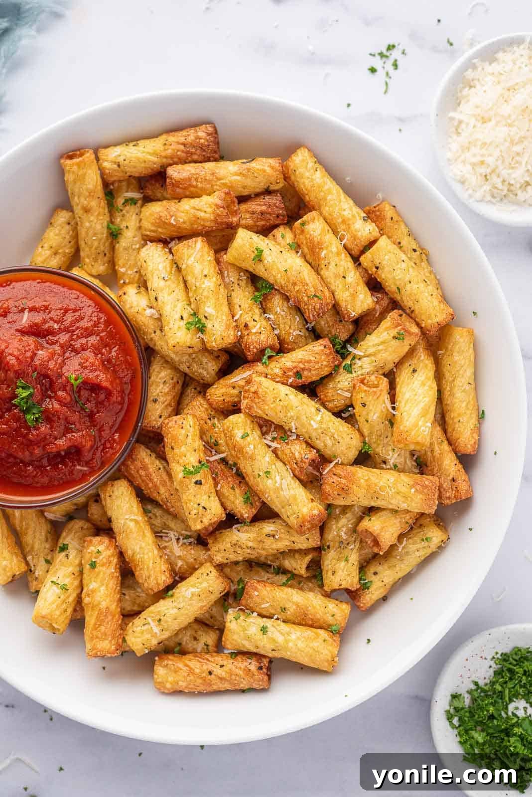 Air fryer pasta chips on a serving platter with a bowl of marinara sauce.