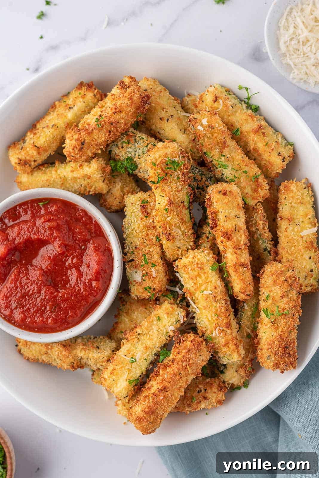 Crispy Air Fryer Zucchini Sticks 2 Air fryer zucchini sticks on a plate with a bowl of marinara.