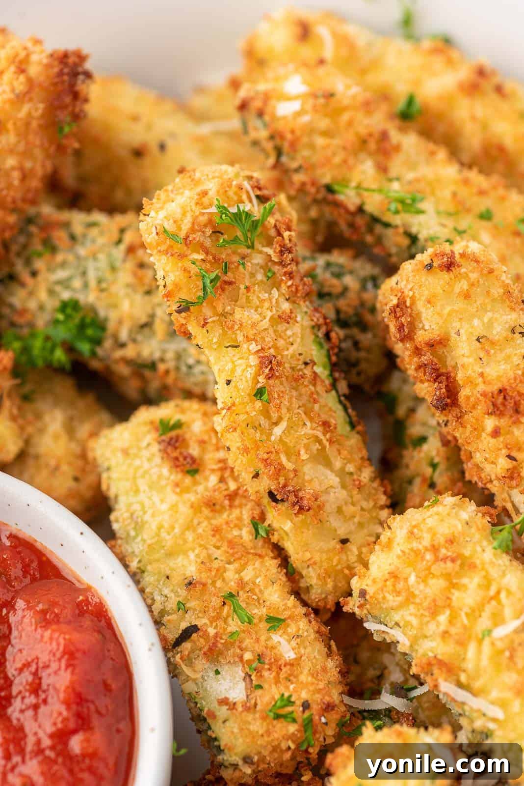 Crispy Air Fryer Zucchini Sticks 9 Close up of breaded zucchini fries on a platter.