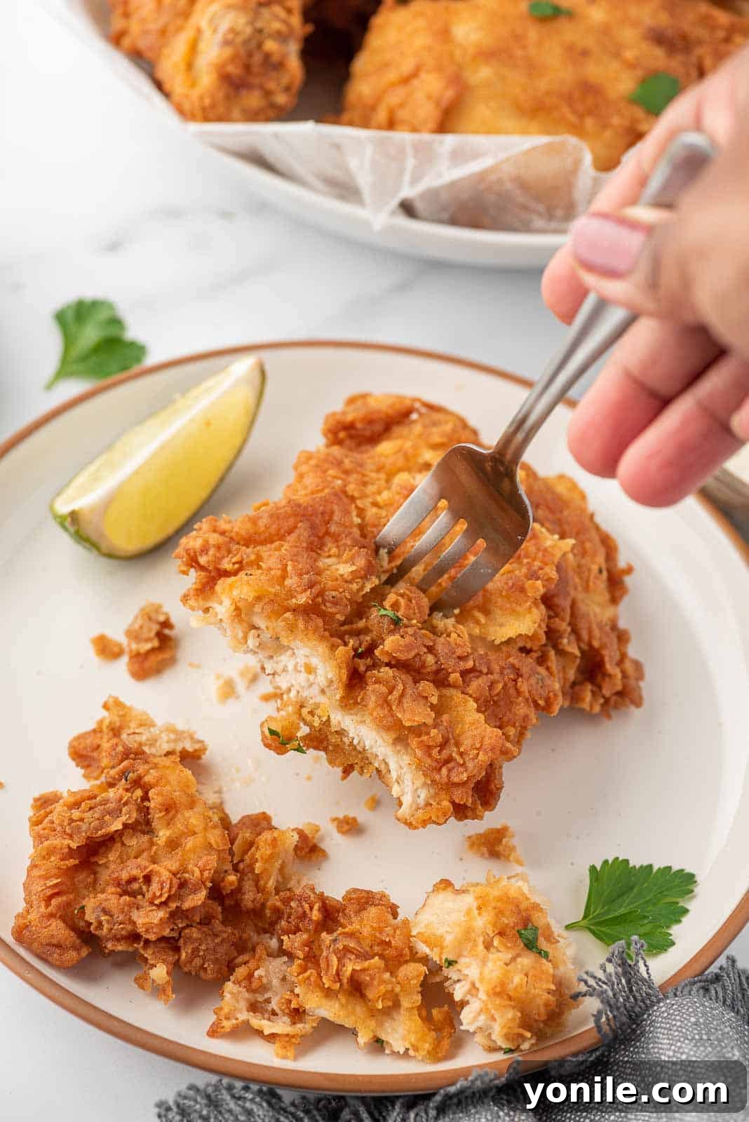 A fork holds a piece of crunchy fried chicken.