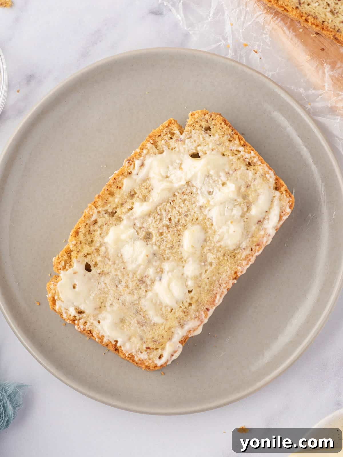 Guilt-Free Keto Sandwich Loaf 9 A slice of gluten free keto bread topped with melting butter sits on a grey plate.