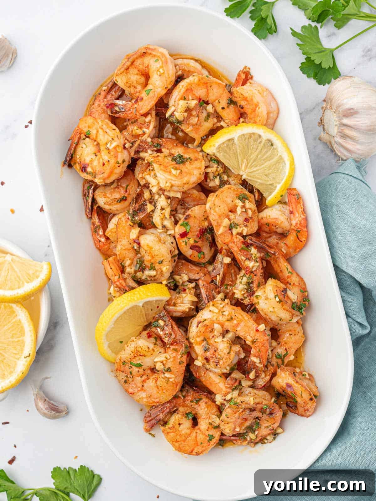 Bright and Buttery Lemon Garlic Shrimp 6 A large tray of garlic and lemon shrimp garnished with lemon wedges and fresh herbs, ready to be served.