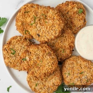 A plate with crispy tuna cakes and a dipping sauce for serving.