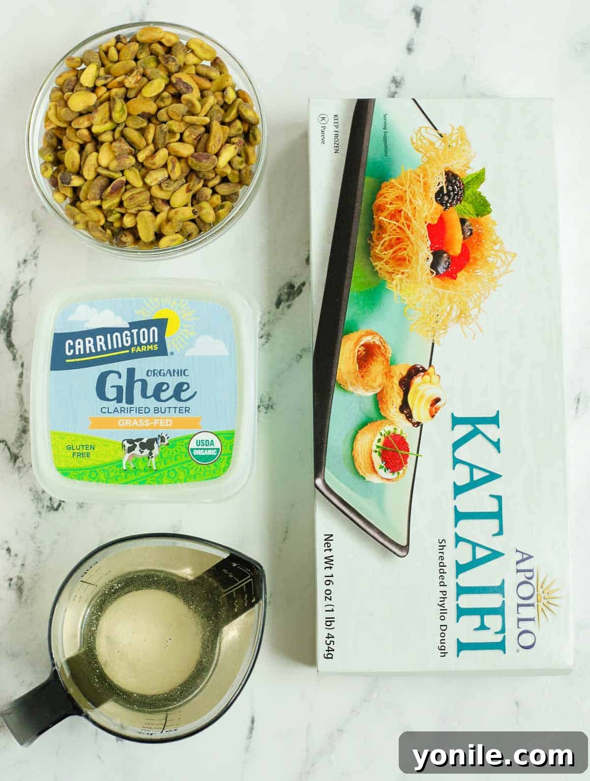 A selection of fresh ingredients including kataifi dough, whole pistachios, and a jar of ghee, ready for baklava preparation.