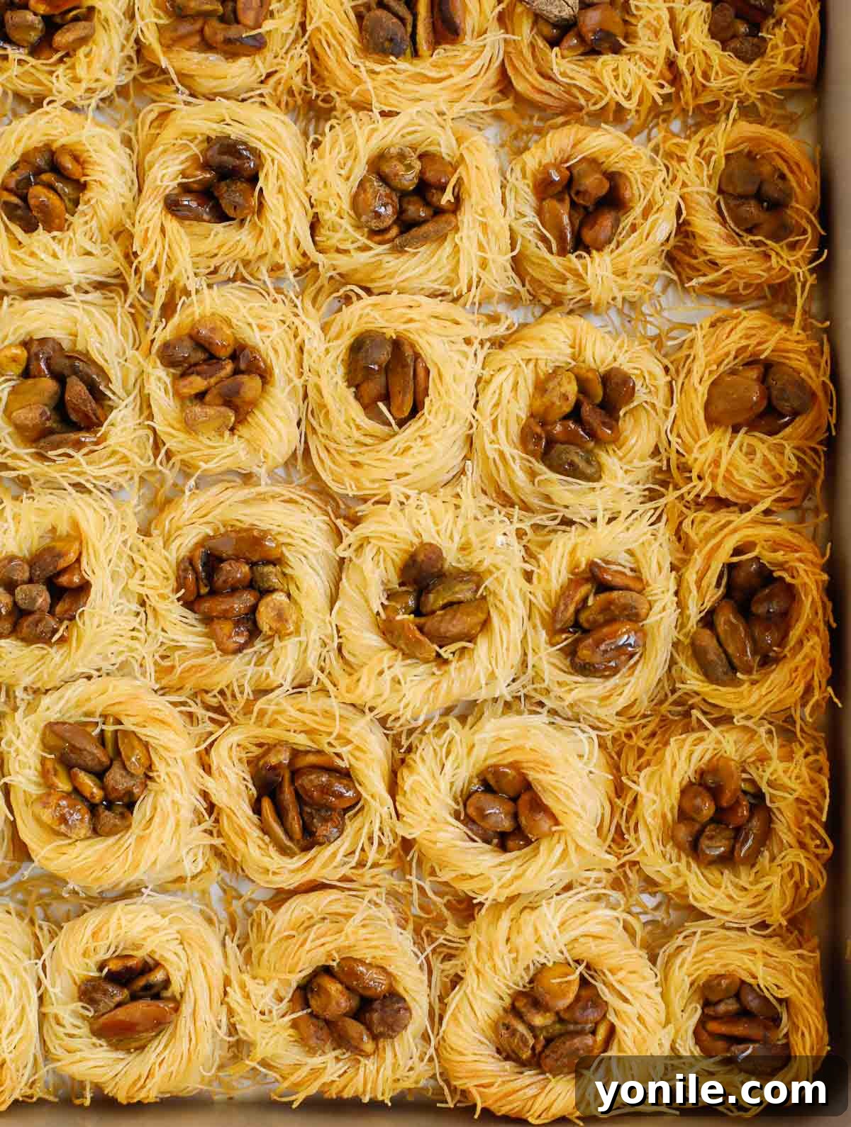Hot Bird Nest Baklava fresh from the oven, being drizzled with cool simple syrup.