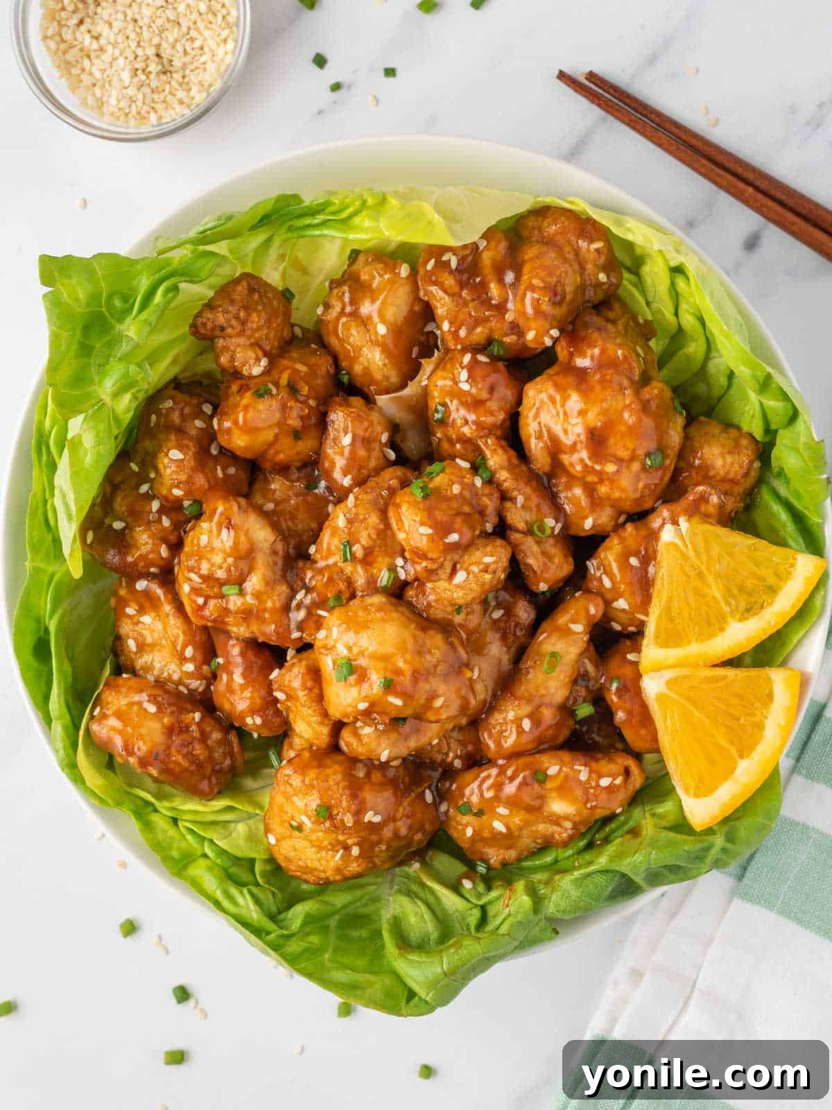 Crispy air fryer orange chicken with a fresh, vibrant sauce, served over a bed of lettuce for a lighter meal.