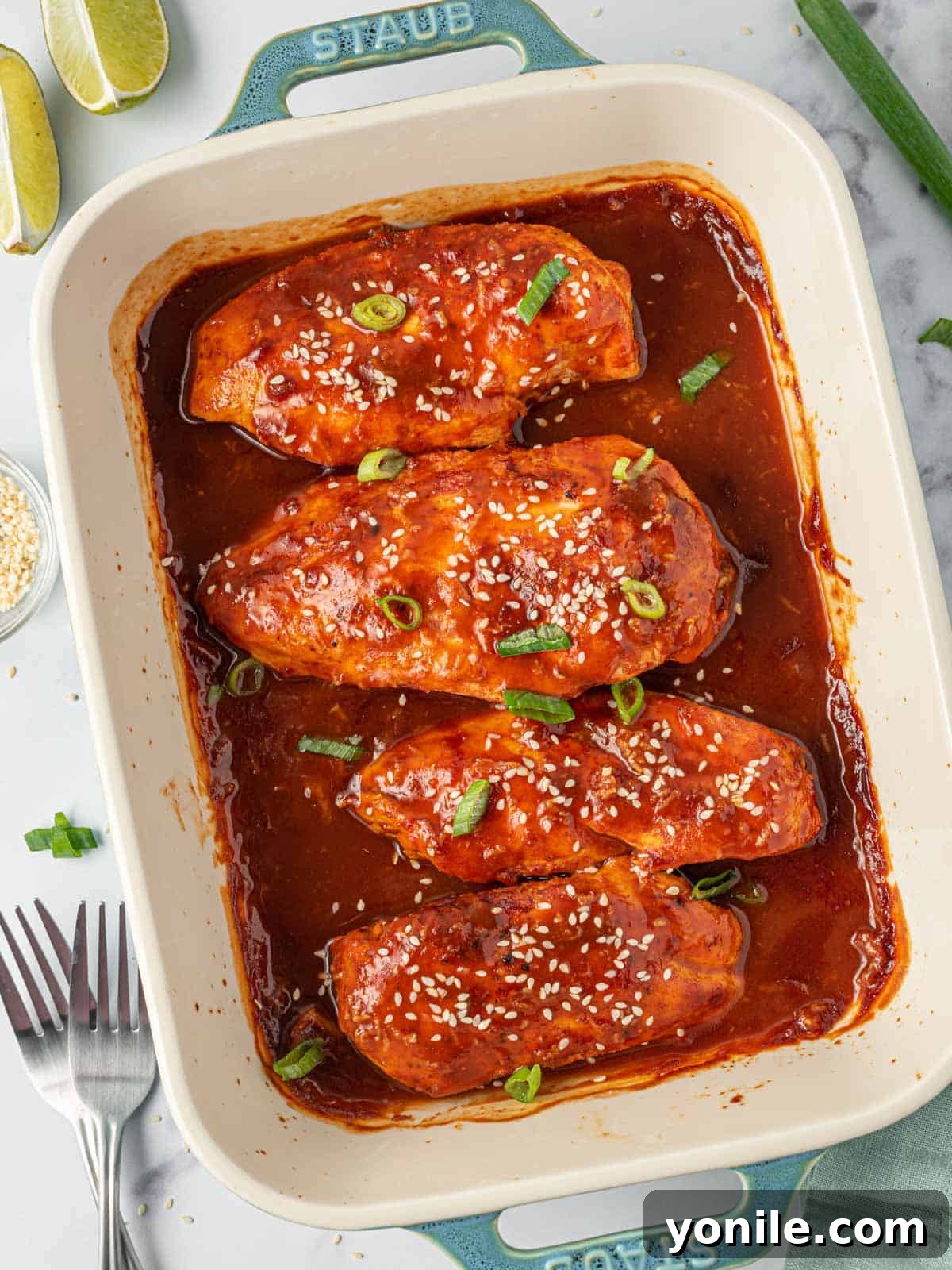 A tray of sweet and spicy honey sriracha chicken, freshly baked and garnished.