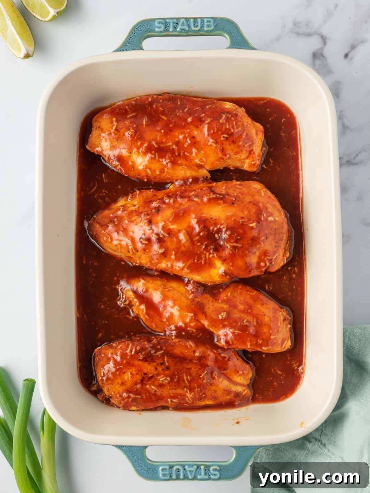 Spicy chicken breast recipe in a baking dish, covered with the delicious honey sriracha sauce.