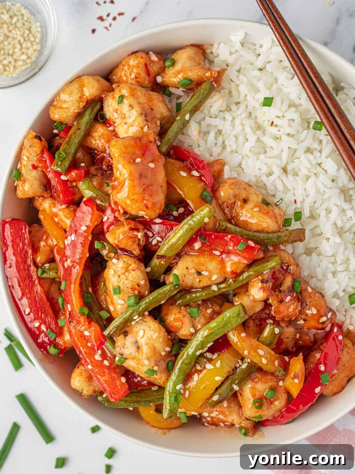 Sweet Thai chili chicken stir fry on a plate with fluffy rice and elegant chopsticks, showcasing vibrant colors and enticing textures.