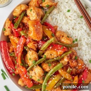 Sweet Thai chili chicken stir fry on a plate with rice and chopsticks.