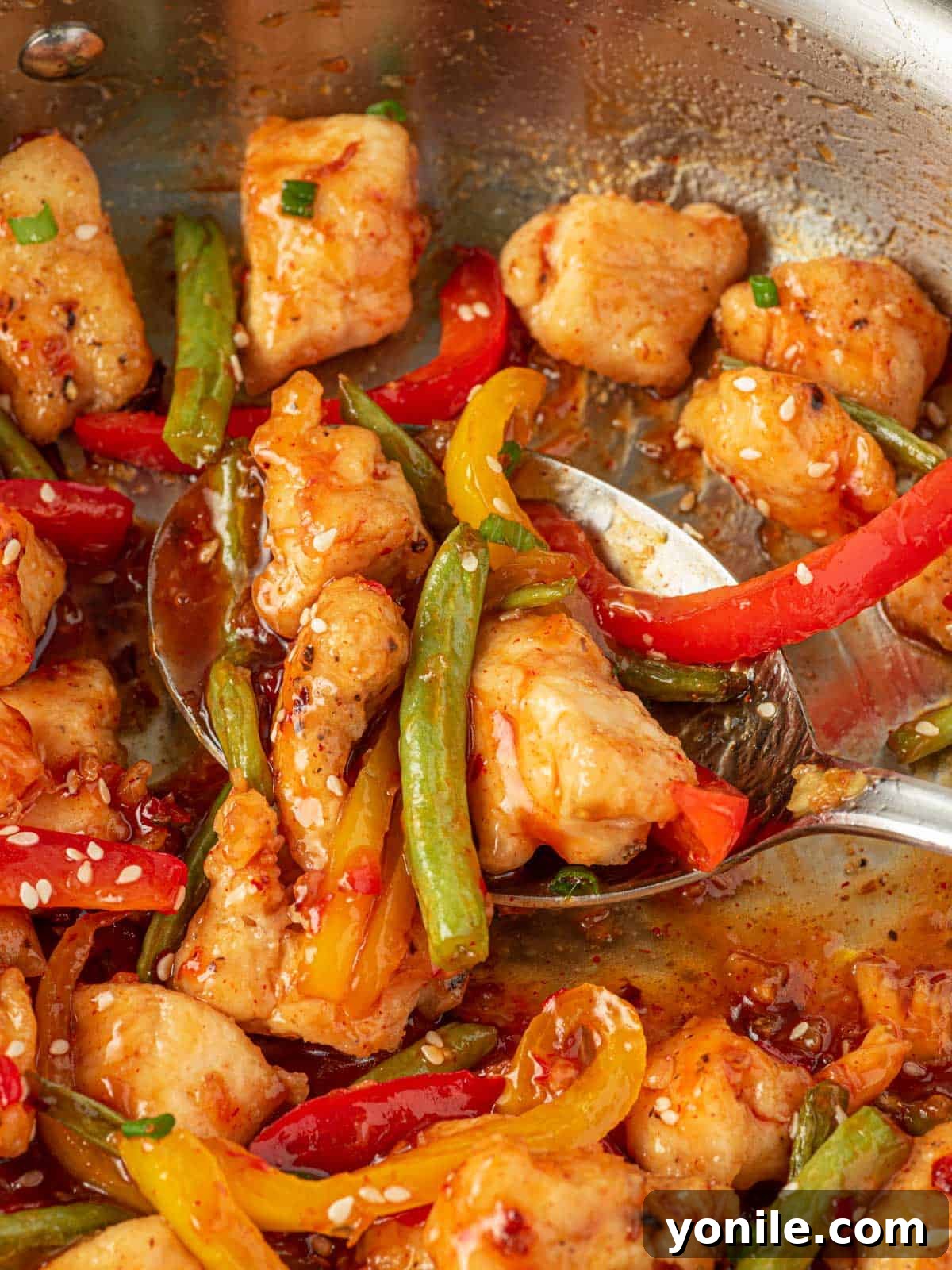 A generous spoonful of homemade crispy chicken and green bean stir fry, ready to be enjoyed.