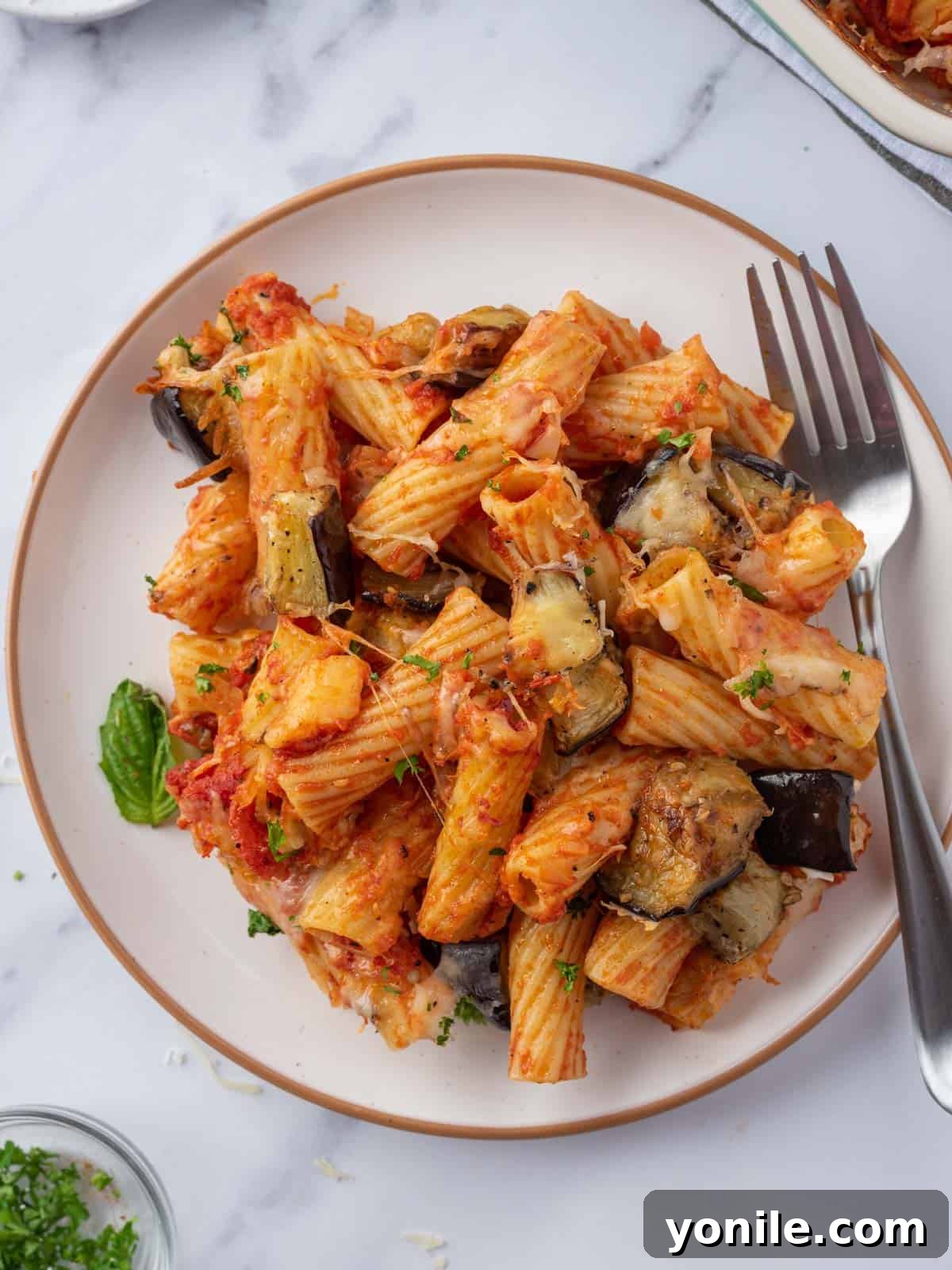 A plate featuring a generous portion of spicy eggplant casserole, with a fork poised to take a bite.