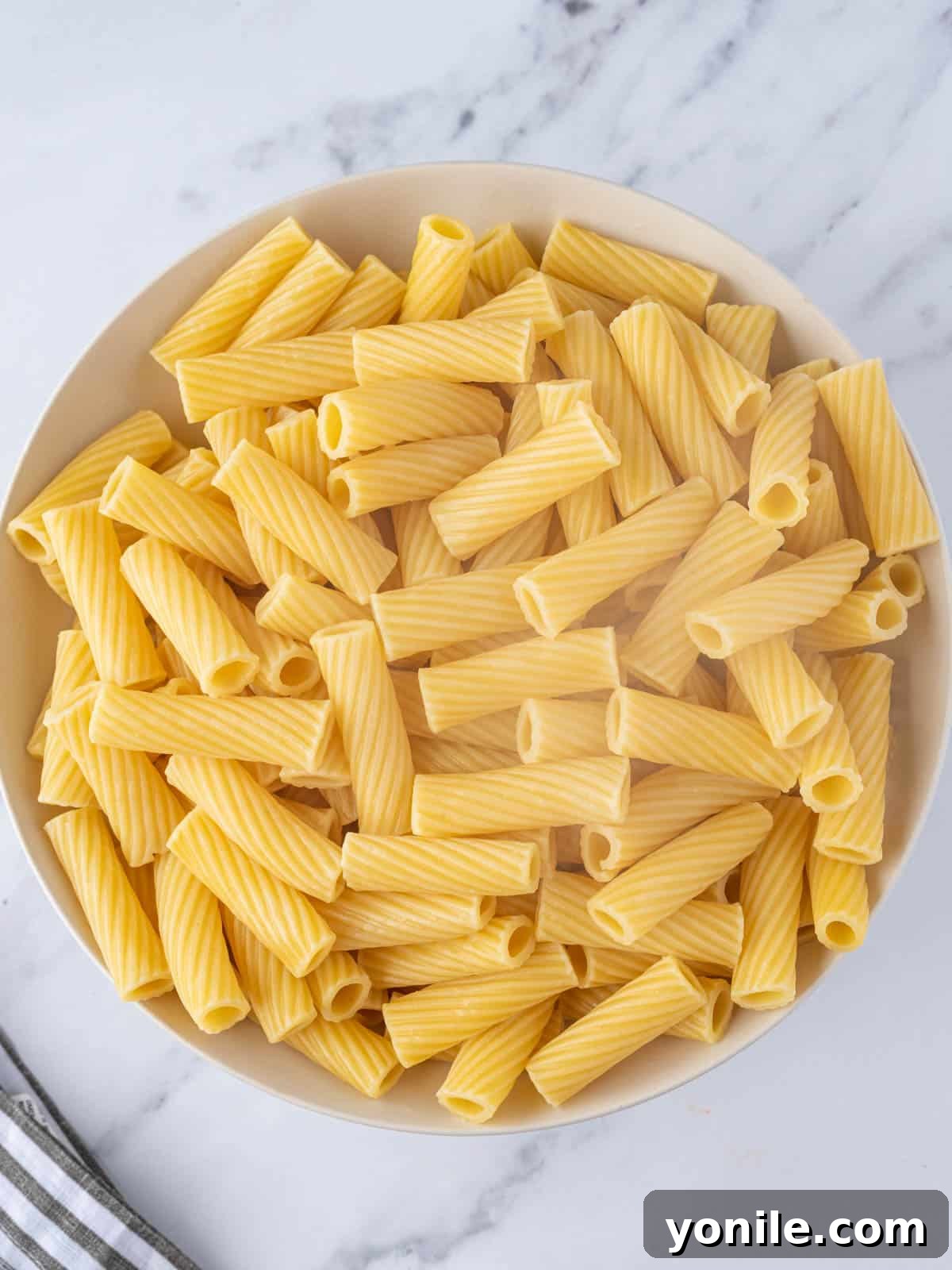 Cooked rigatoni pasta resting in a large bowl, ready for sauce.