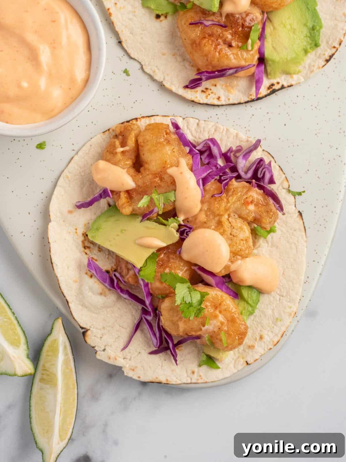 Quickfire Dynamite Shrimp Tacos 10 An assembled spicy shrimp taco with bang bang sauce sits on a serving platter, ready to be enjoyed.