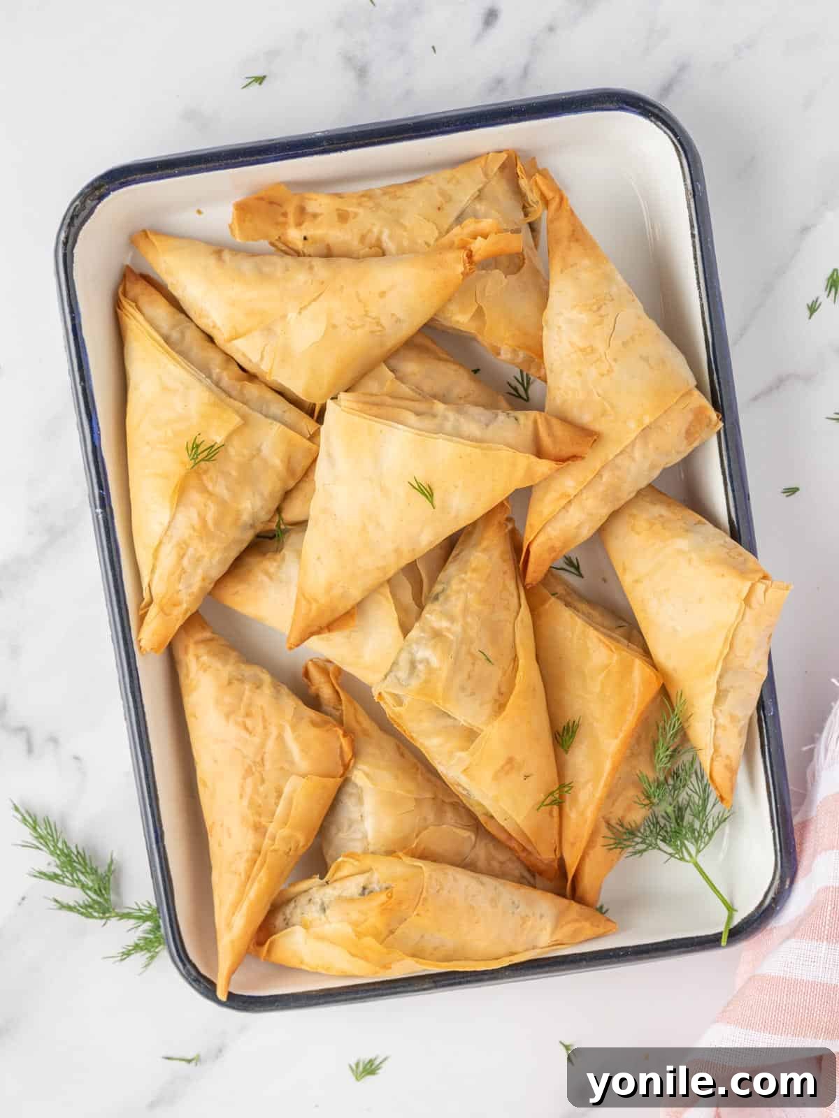Simple Spanakopita Bites 2 Spinach and feta triangles on a platter, showcasing the crispy phyllo and vibrant filling.