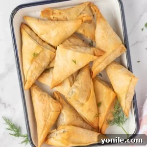Simple Spanakopita Bites 11 Spinach and feta triangles on a platter, ready to be served.