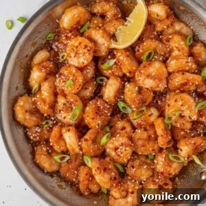 Dynamite Prawns 11 Garnished firecracker shrimp in a skillet with a lemon wedge.