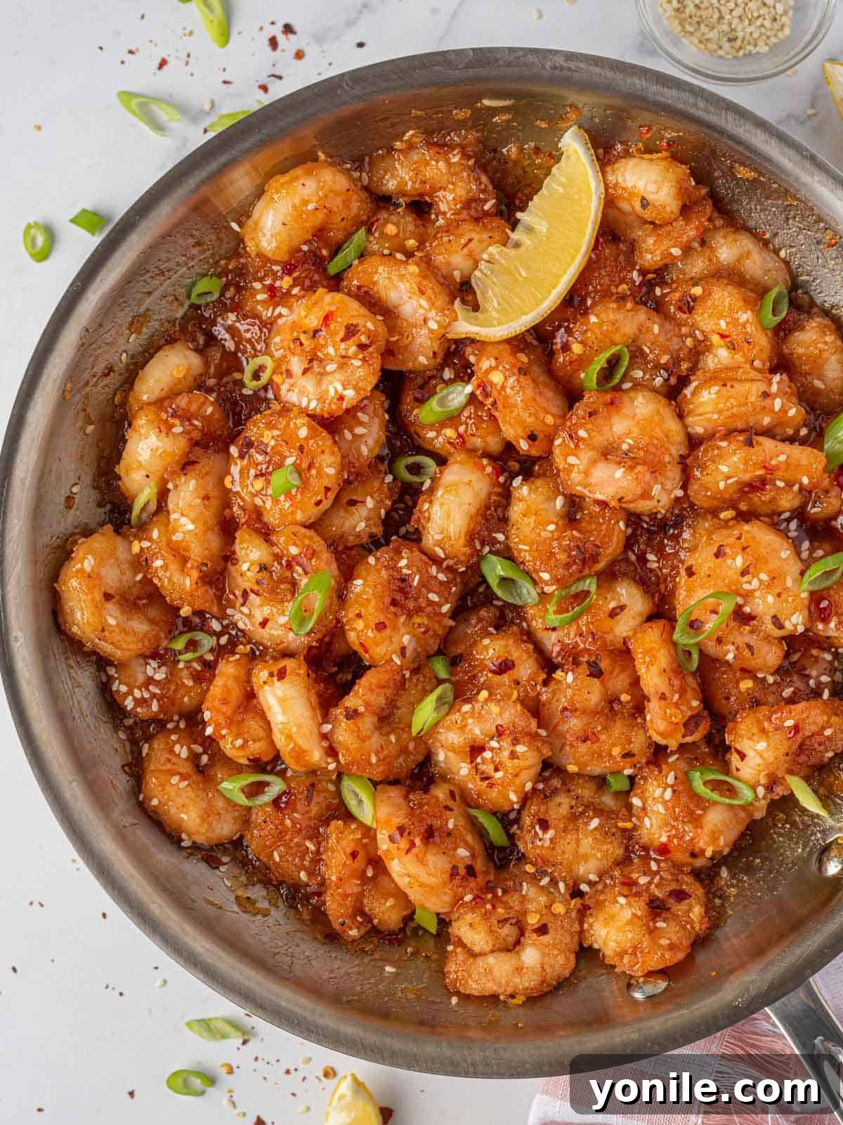 Dynamite Prawns 10 Garnished firecracker shrimp in a skillet with a lemon wedge.