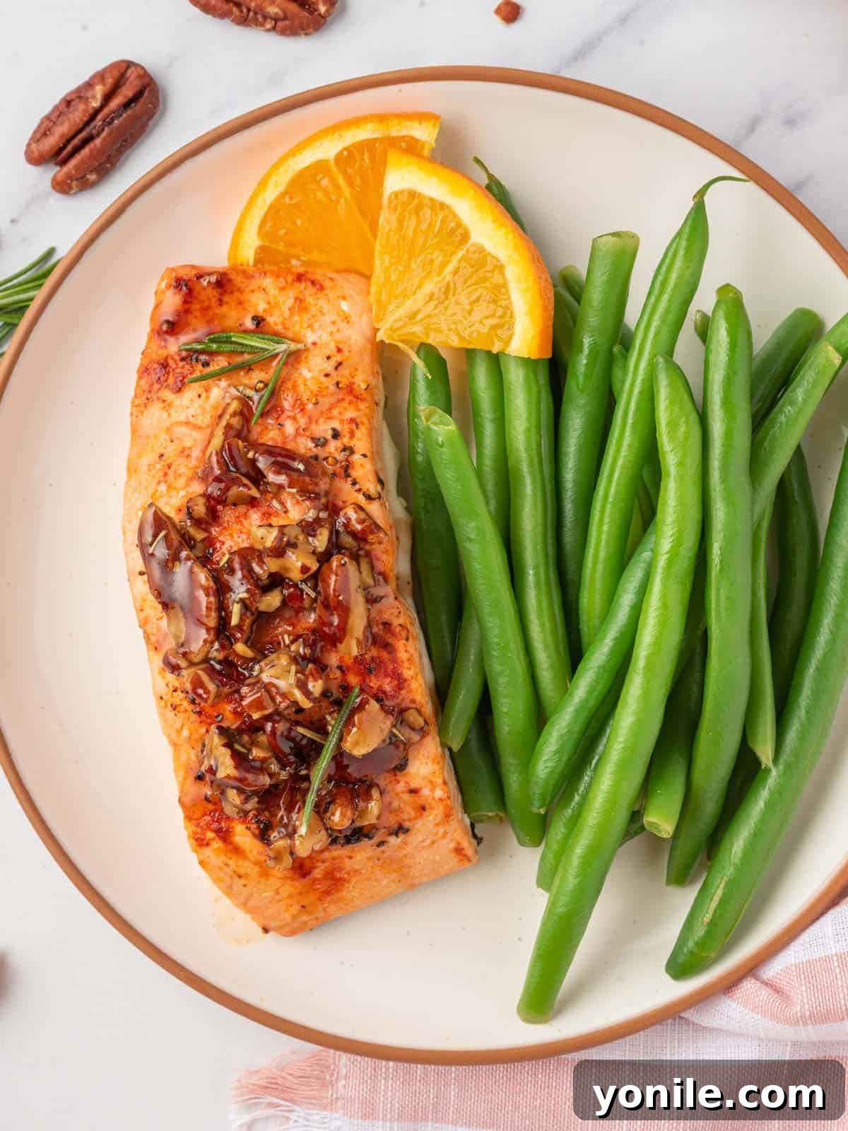 A plate with green beans and salmon with pecans, showcasing a complete meal.