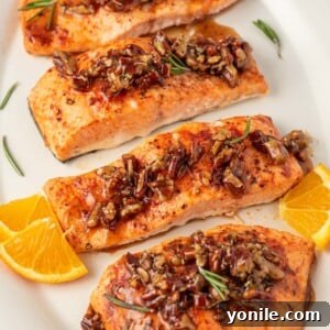 Salmon with pecans and maple syrup on a platter with oranges as garnish.