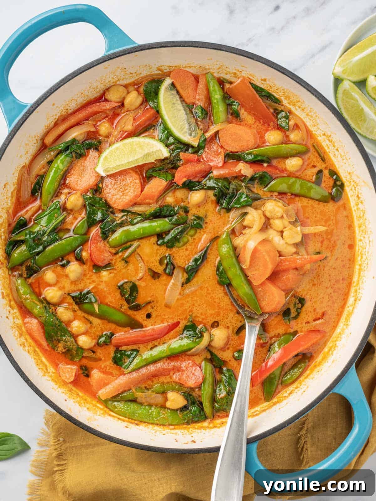 Thai curry with vegetables in a pot with a serving spoon.