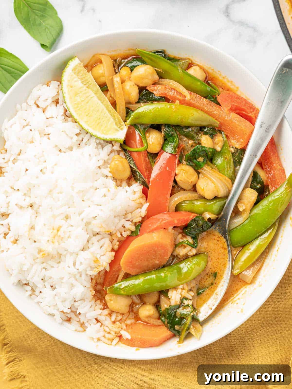 Red thai curry in a bowl with rice and a spoon.