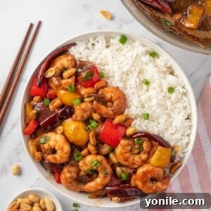 Kung pao shrimp recipe in a bowl with rice and chopsticks on the rice.