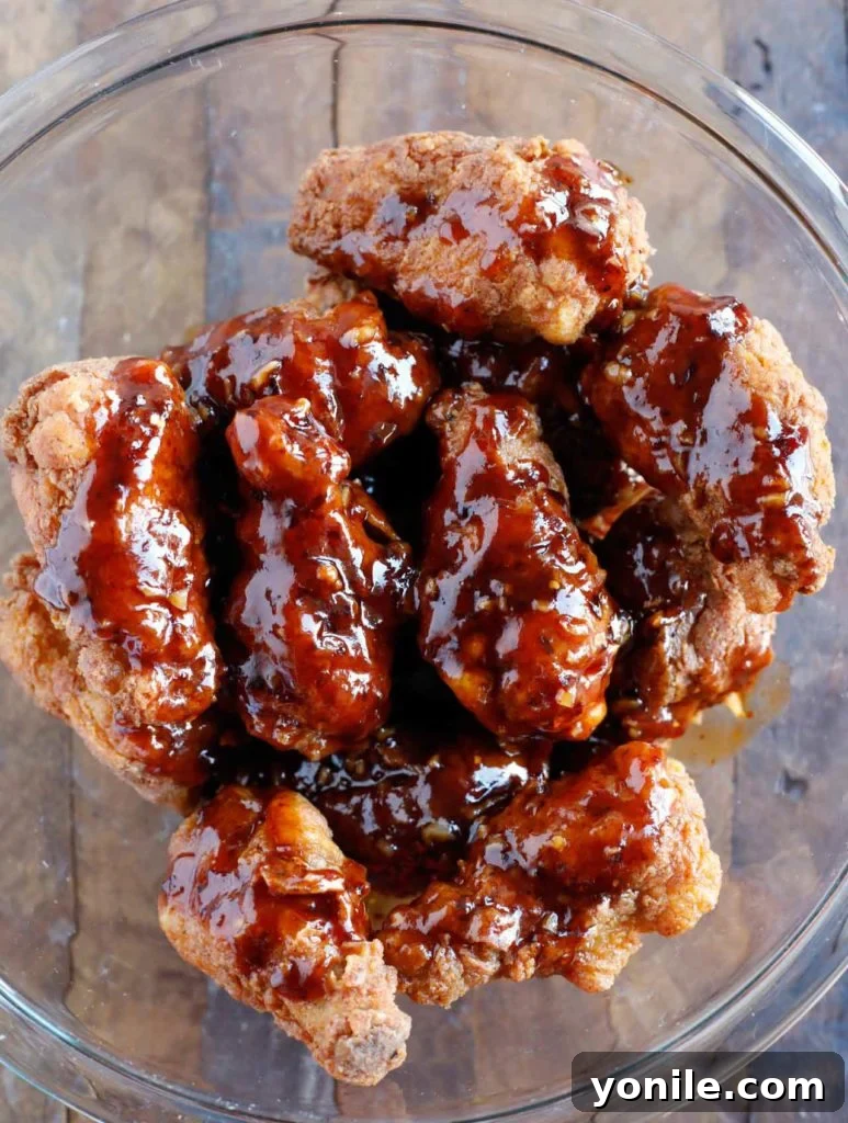 Freshly fried chicken wings, golden and crispy, draining excess oil on a wire rack, ready for the sauce.
