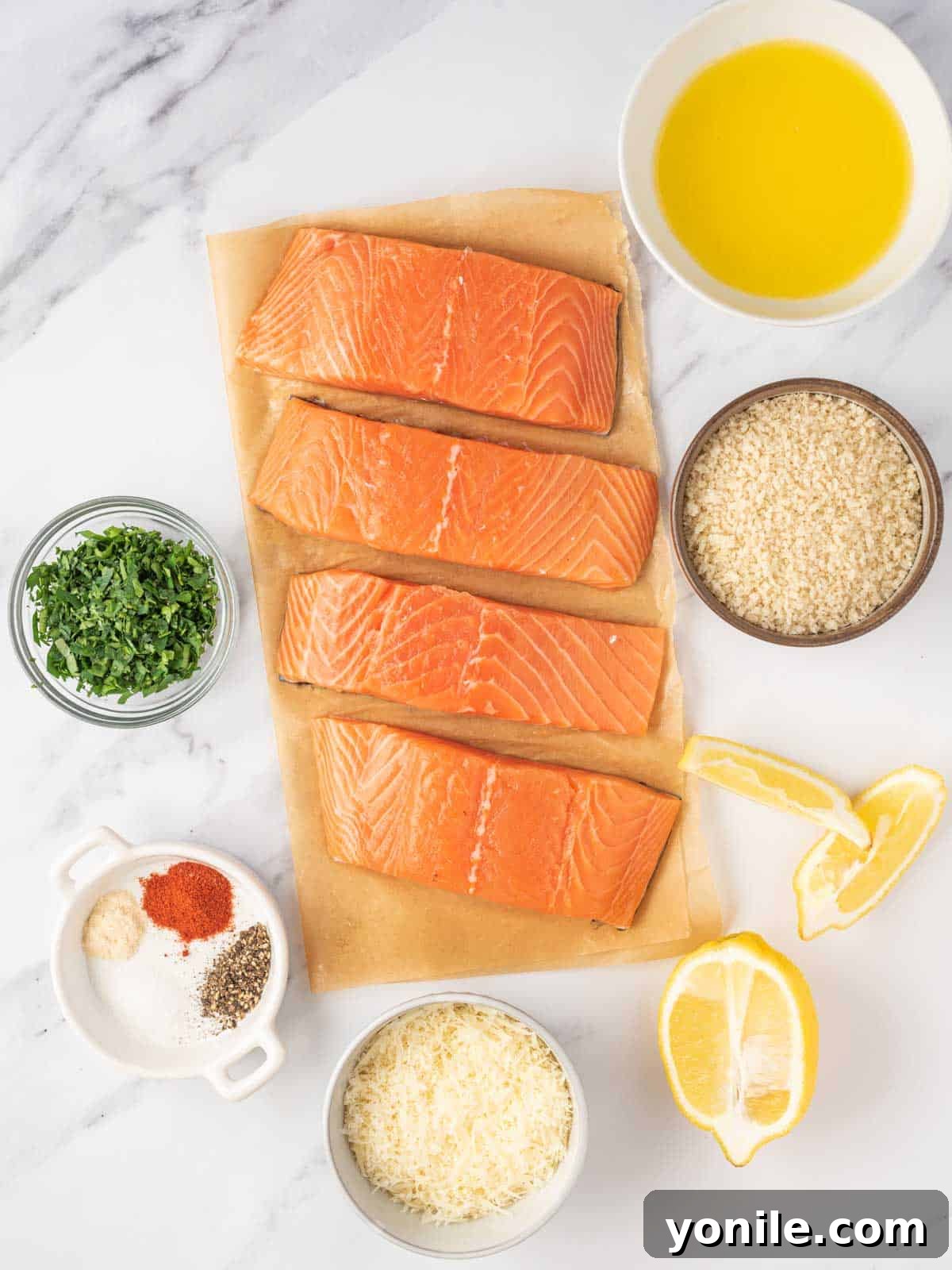 Fresh ingredients laid out for making crispy baked salmon, including salmon fillets, butter, panko breadcrumbs, parmesan cheese, parsley, and various seasonings.