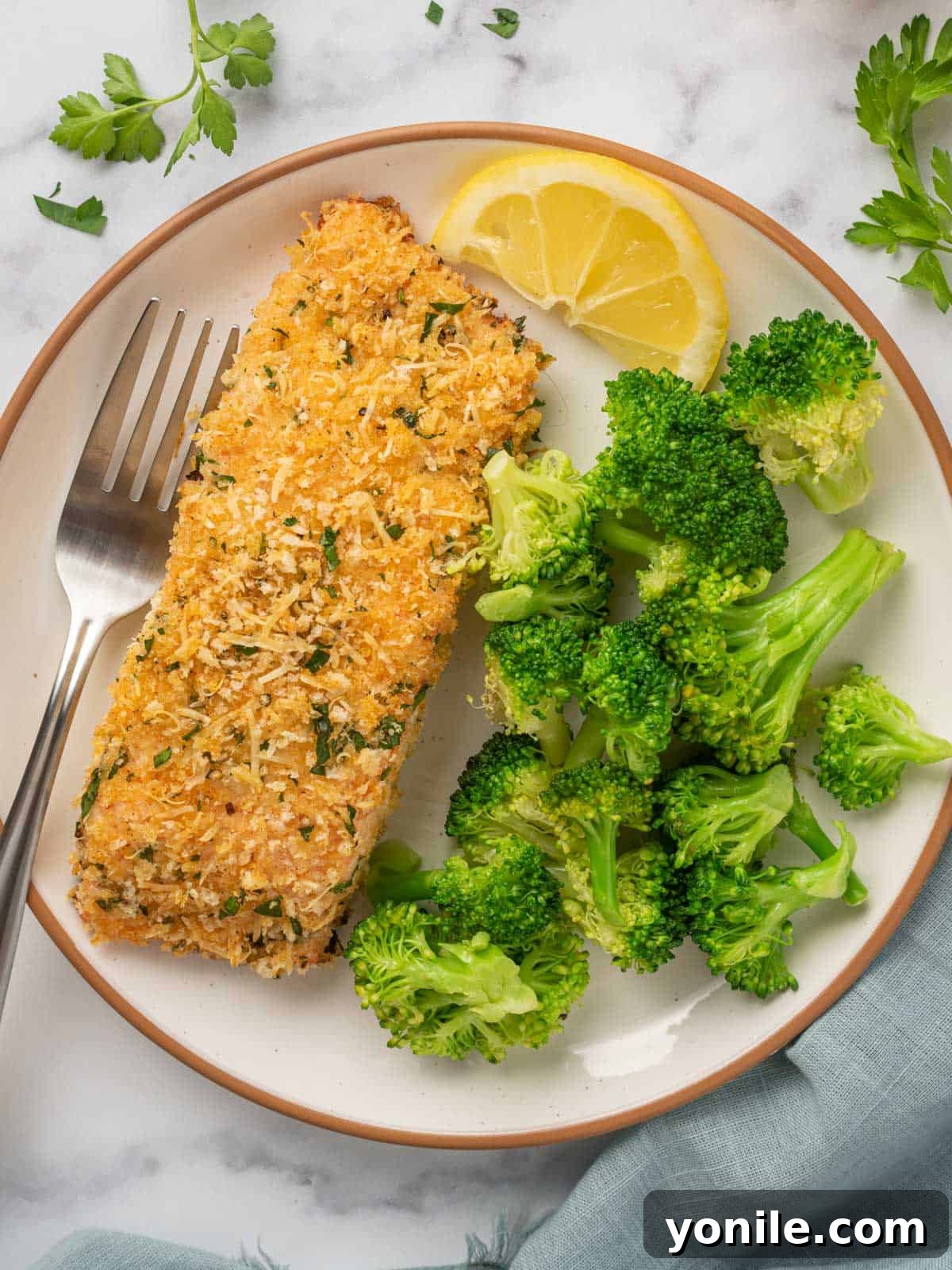 A perfectly cooked crispy baked salmon fillet, flaked with a fork, served on a white plate alongside vibrant green steamed broccoli, ready to enjoy.