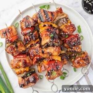 A pile of grilled chicken teriyaki skewers on a round platter.