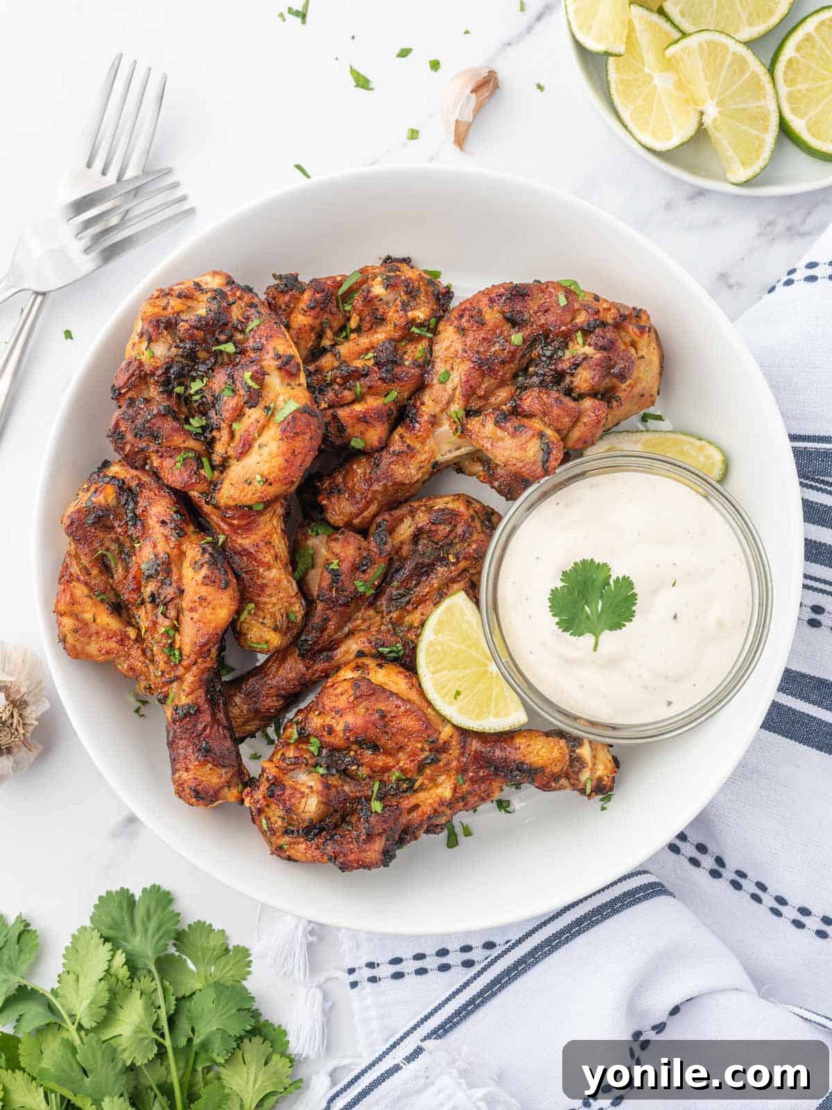 Blossoming Drumsticks 2 Crispy air-fried butterfly drumsticks marinated in cilantro lime sauce, served on a plate with fresh lime.
