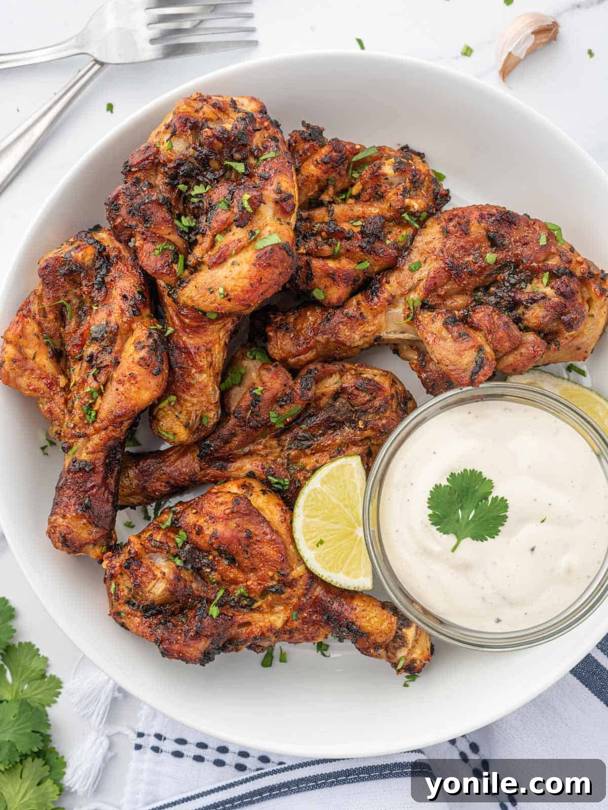 Blossoming Drumsticks 9 A plate of air-fried butterfly drumsticks with a creamy white dipping sauce on the side, ready to eat.
