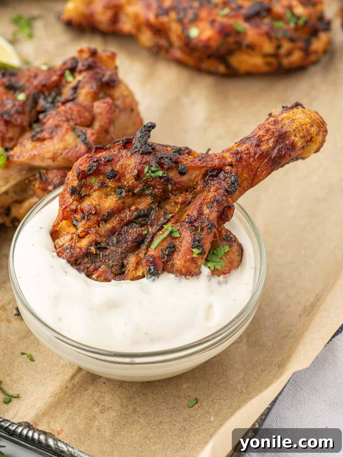Blossoming Drumsticks 10 Cilantro lime chicken legs being dipped into a creamy white sauce, highlighting their golden-brown and crispy texture.