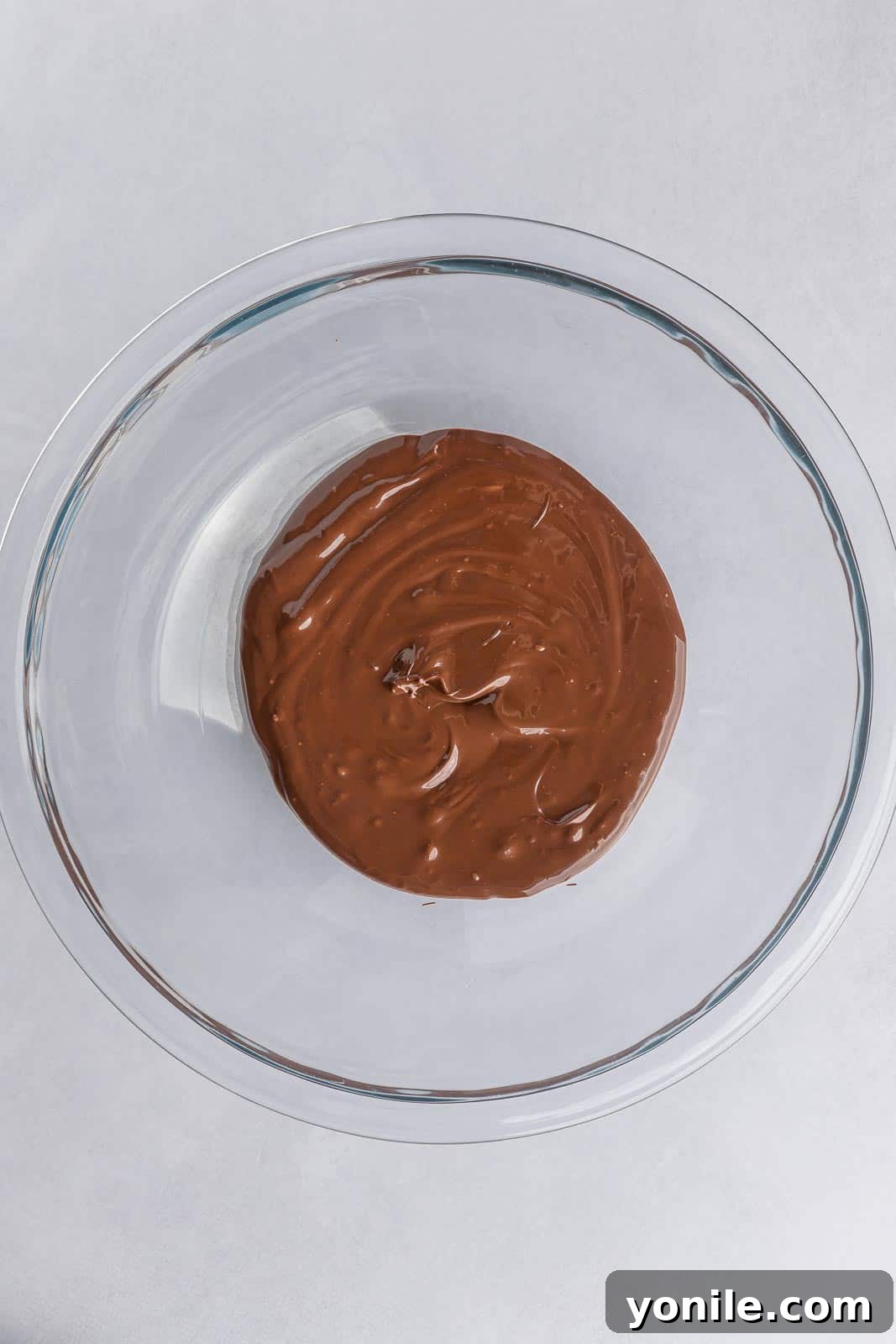 Rich, dark melted chocolate in a bowl, glistening and ready for the next step in the filling preparation.