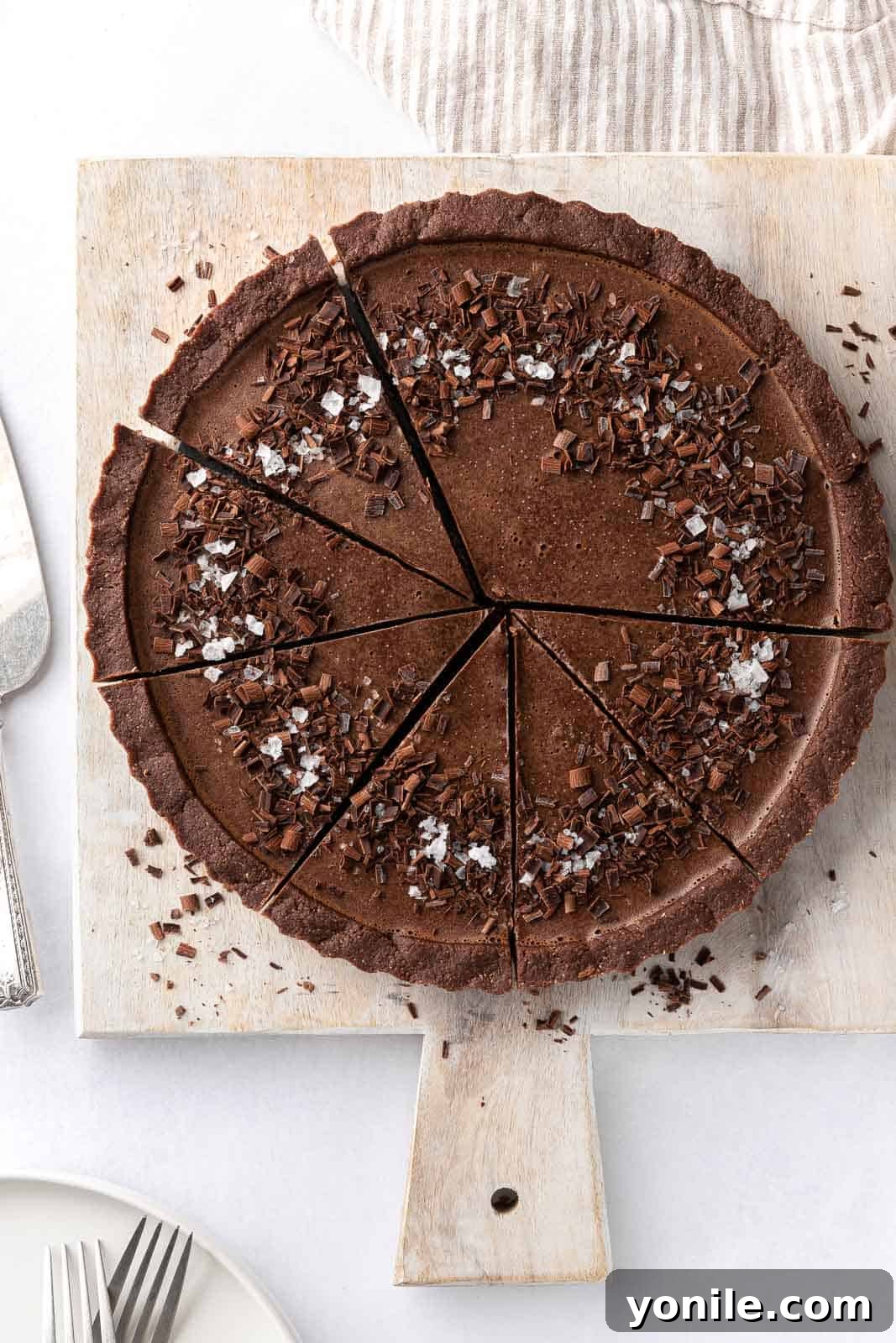 A perfectly sliced vegan chocolate pie presented on a wooden board, showcasing its rich filling and crumbly crust.