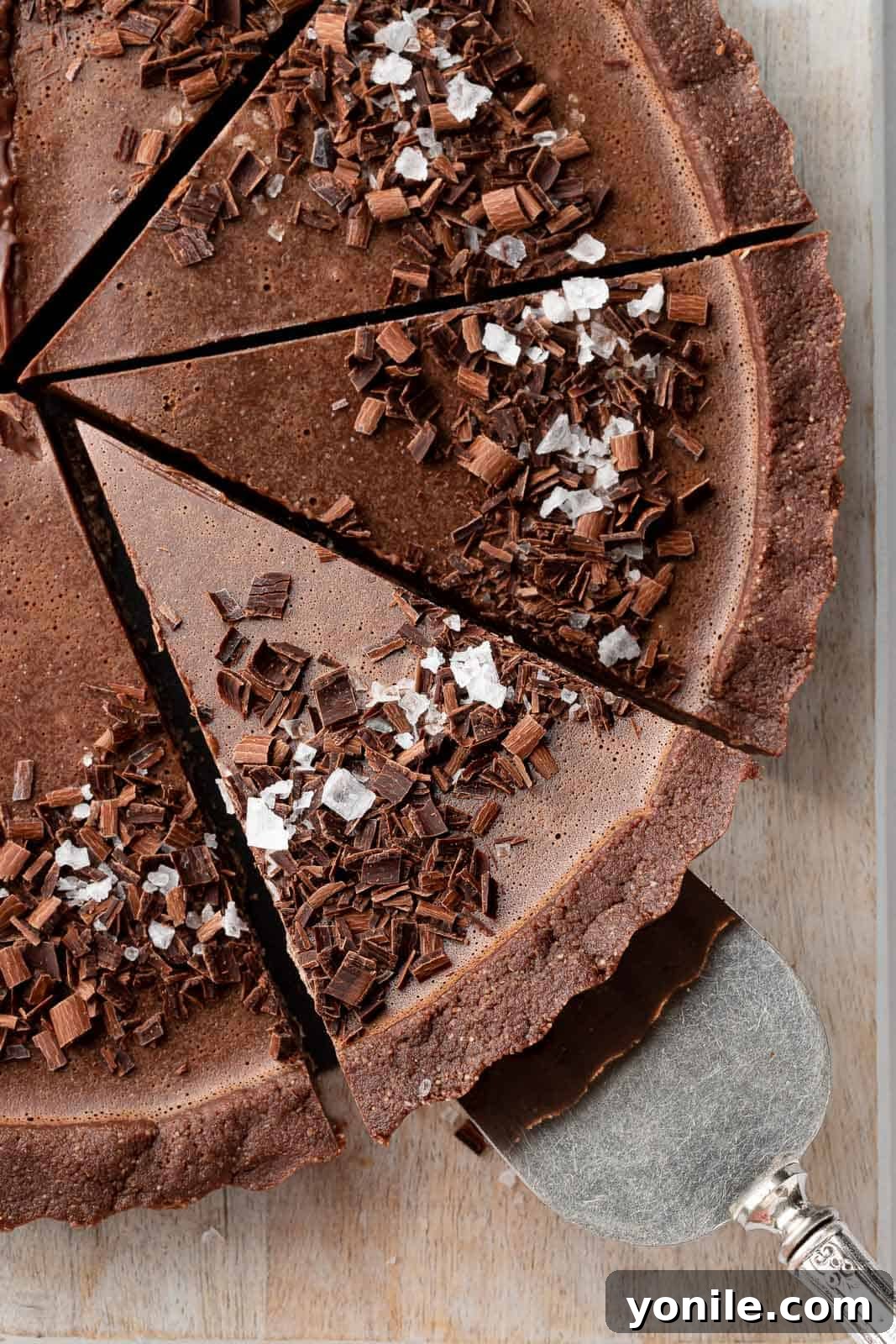 A delectable slice of vegan no-bake pie being gently lifted on a cake server, highlighting its smooth texture and rich color.