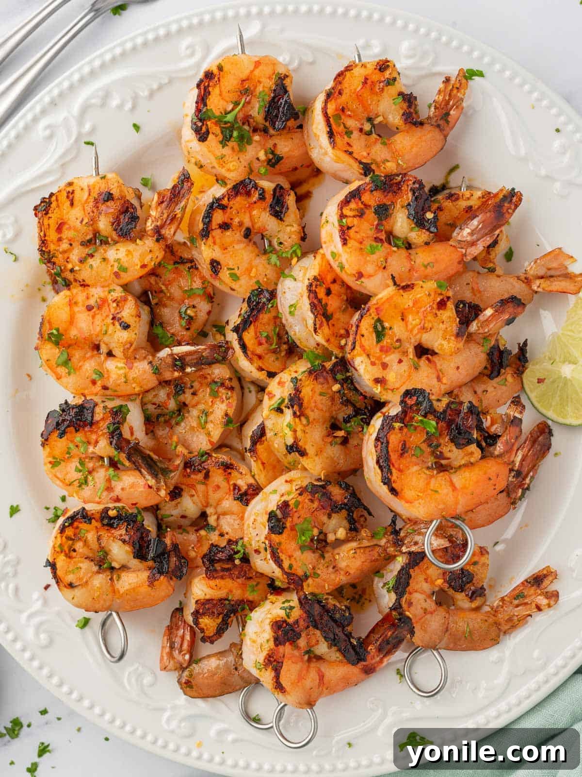 Zesty grilled garlic shrimp skewers on a large platter, garnished and ready to be served.