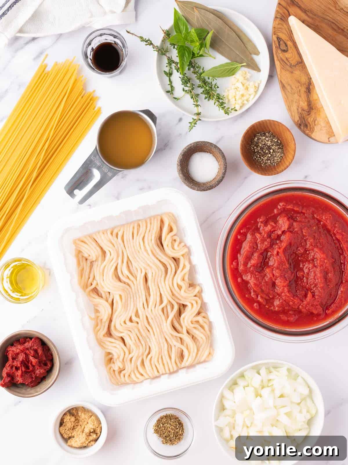 All the fresh ingredients meticulously arranged for preparing a homemade chicken spaghetti bolognese.