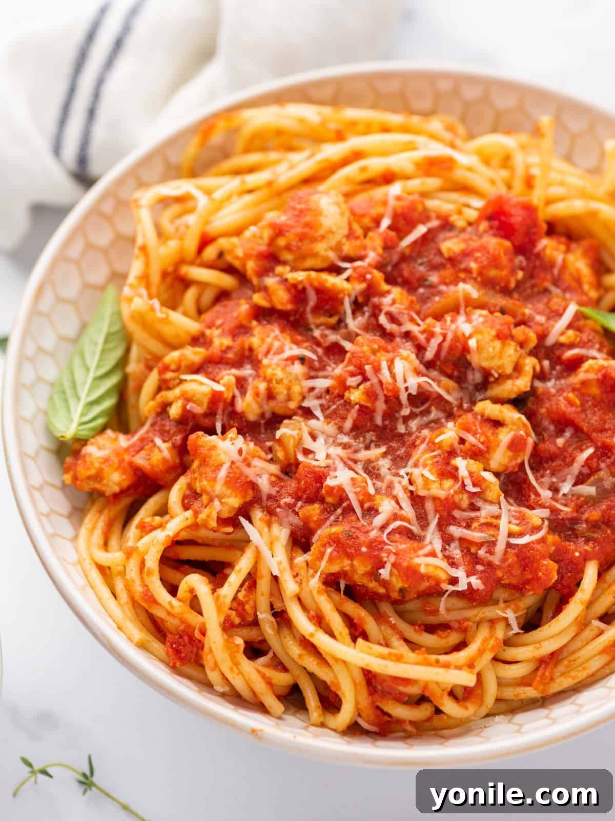 A beautifully presented bowl of chicken spaghetti bolognese, garnished and ready to be enjoyed.