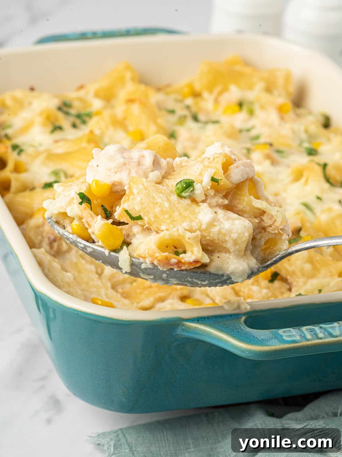 Velvety Tuna Pasta Casserole 11 A spoon serves up a helping of creamy tuna and noodles from a baking dish.