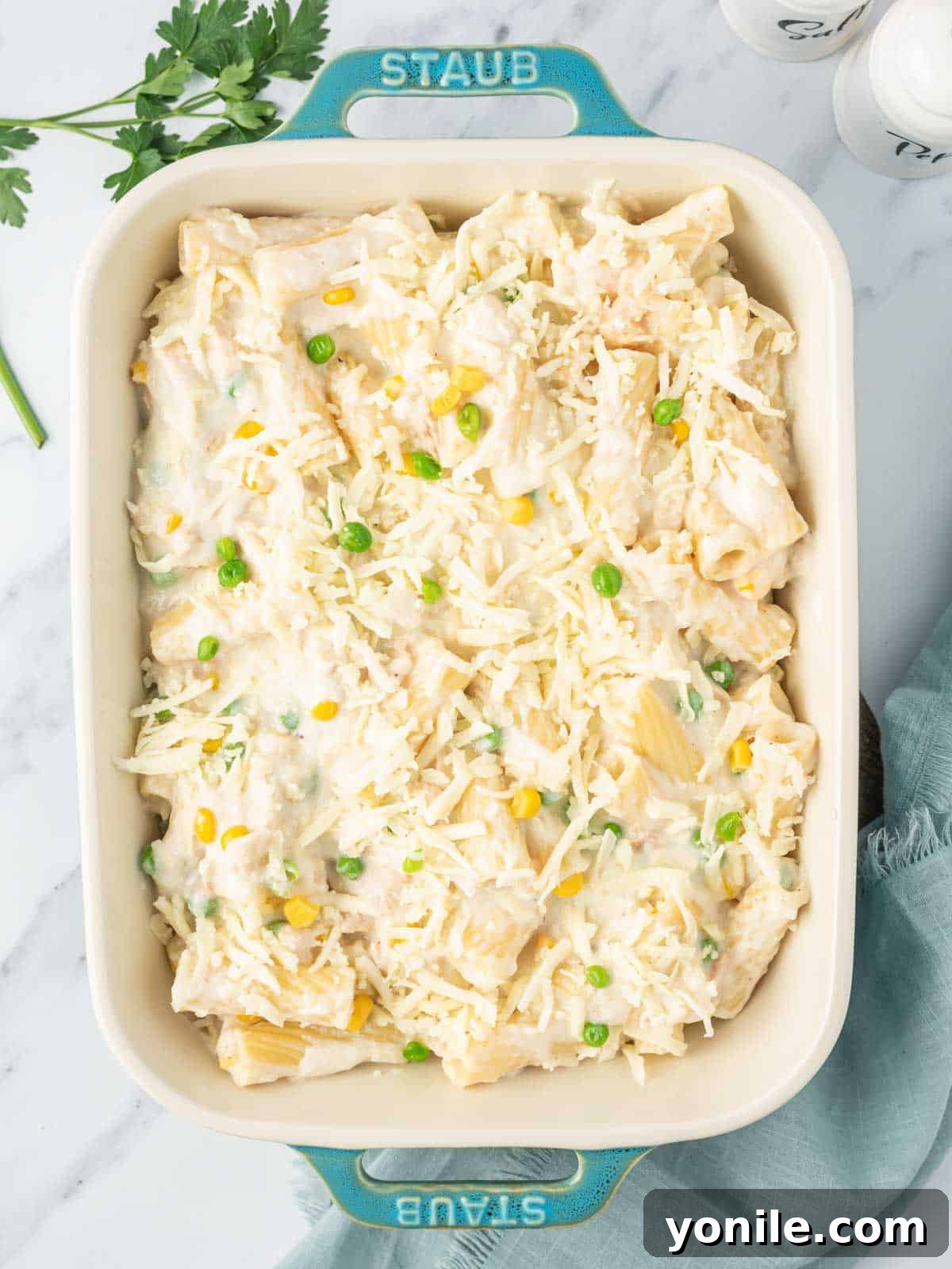 Velvety Tuna Pasta Casserole 8 Tuna and noodles mixture in a casserole dish, topped with cheese, ready to be baked.