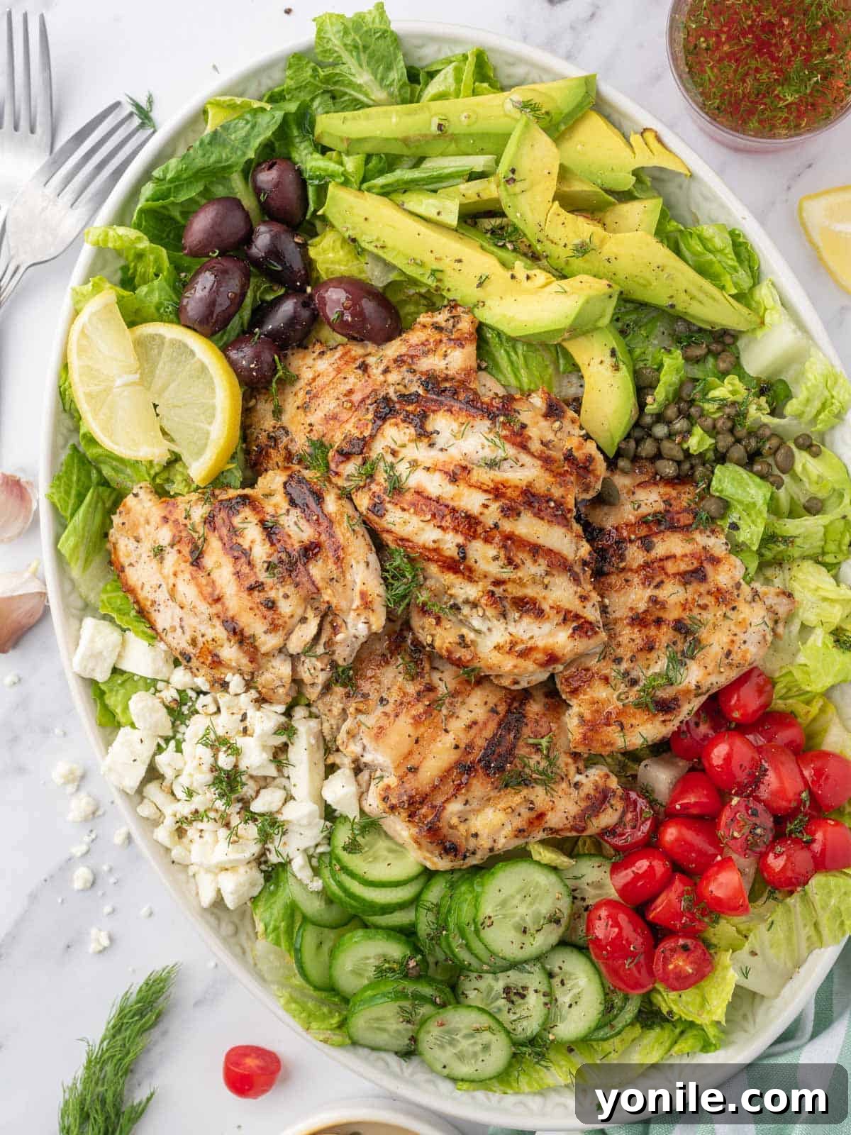Vibrant Greek Grilled Chicken Salad 2 Greek chicken salad recipe on a platter with dressing on the side.